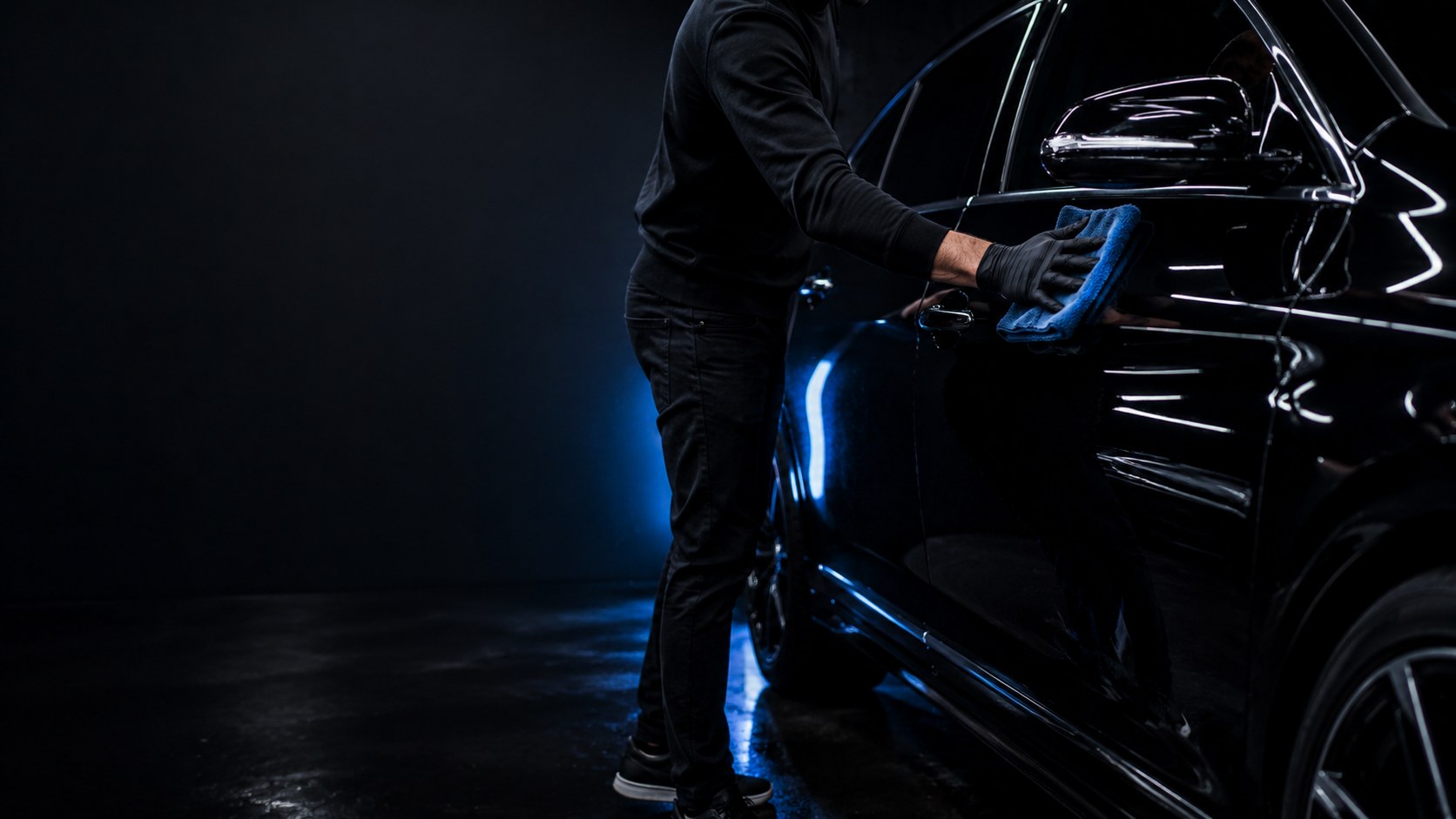 Detailer wiping glossy black car